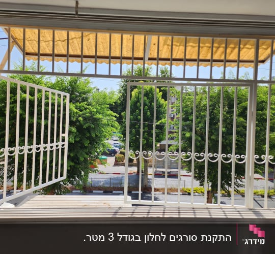 חלון עם סורגי מתכת לבנים פתוחים חלקית